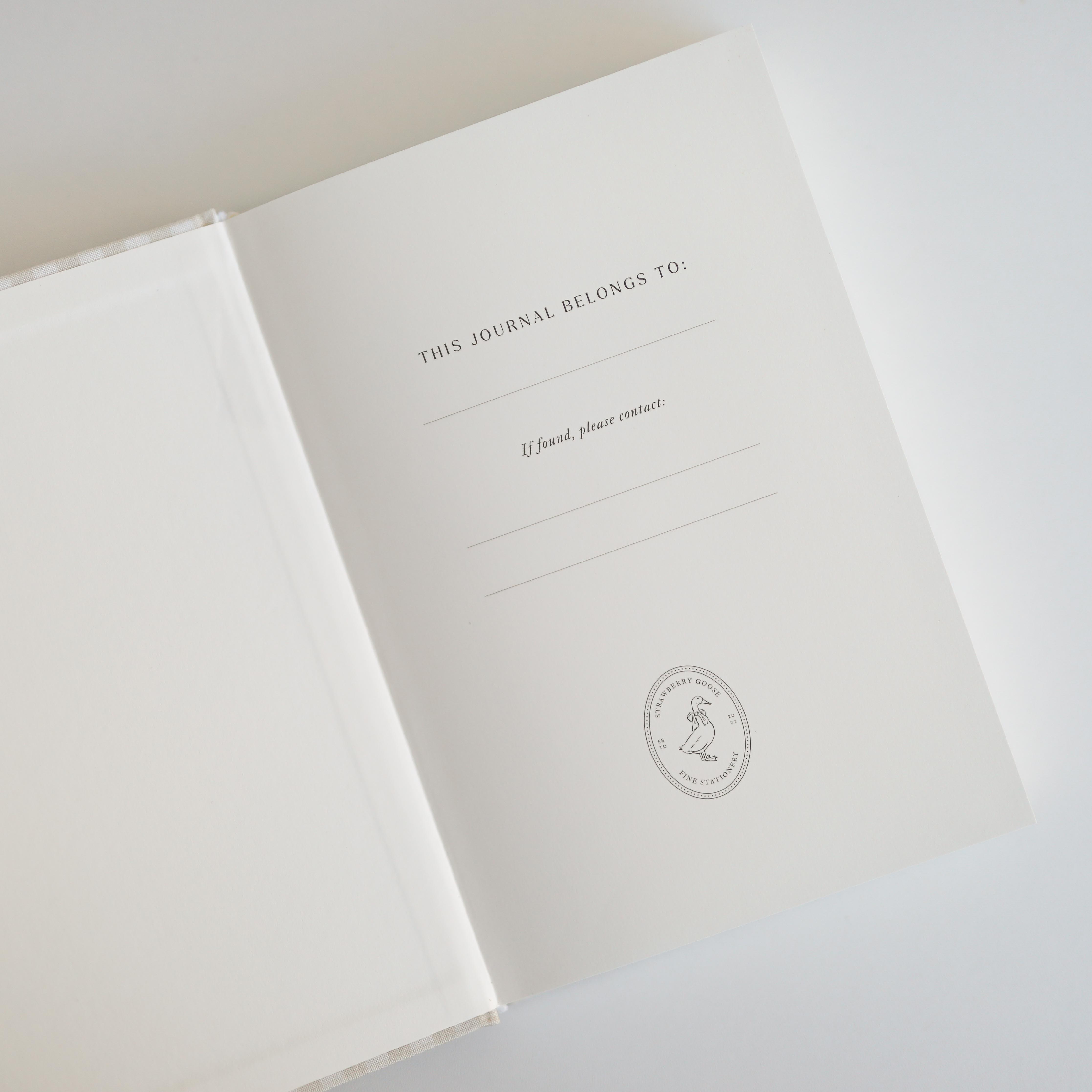 Journal with 'This Journal Belongs To' text and a logo on a light background